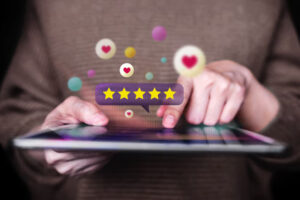 User interacting with a digital tablet as five-star reviews and heart icons float around, illustrating positive customer feedback – 99exch Review.